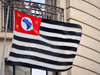 So Paulo, Brazil: So Paulo flag flying in a downtown building - composed of 13 horizontal black and white stripes, on a red canton, a silhouette map of Brazil appears in blue on a white circle, a small yellow star appears in each corner of the canton - photo by M.Torres