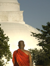 near Yala National Park / Ruhuna, Southern Province, Sri Lanka: Buddhist monk with dagoba in background - stupa - photo by B.Cain